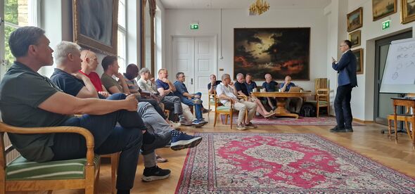 People sitting i a circle in a large room. Photo.