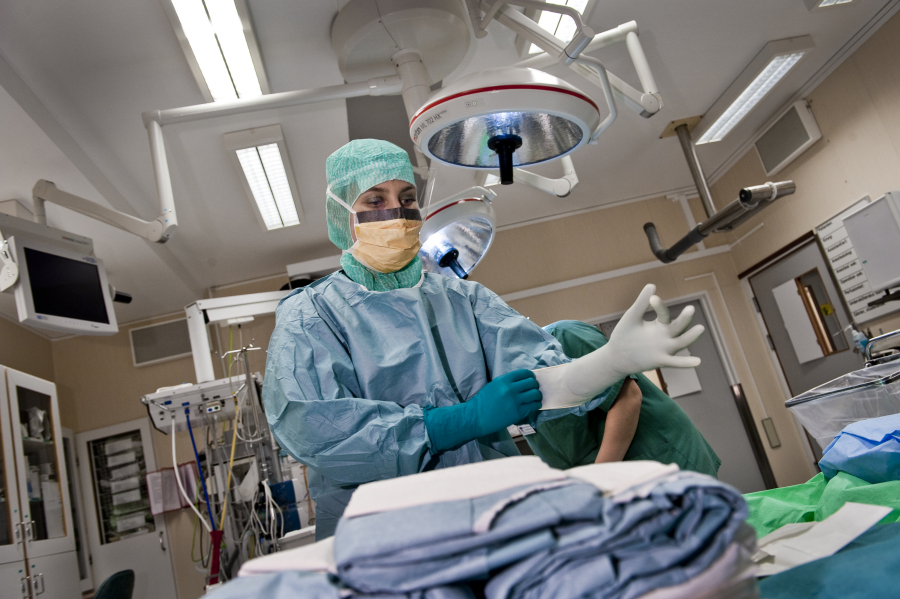 Surgeon in operation theatre putting on plastic gloves. Photo.
