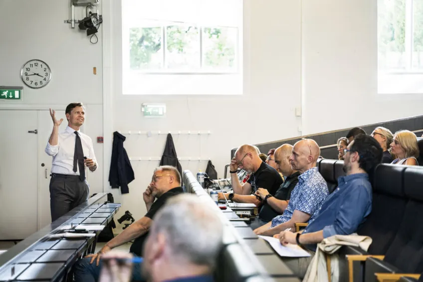 Smiling man lecturing in a lecture hall. Photo.